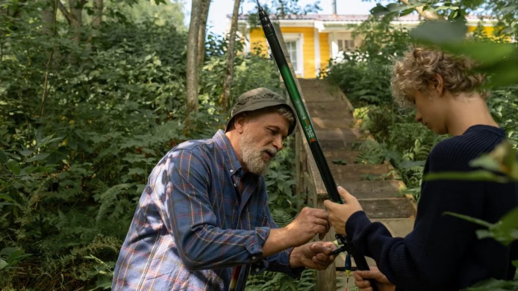 Grandfather and grandson preparing fishing rods outdoors, enjoying quality family time in nature.