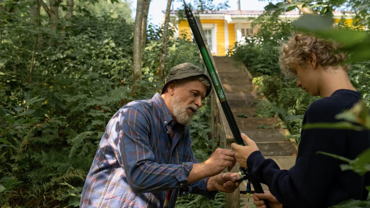 Grandfather and grandson preparing fishing rods outdoors, enjoying quality family time in nature.